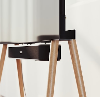 A modern television set up on sleek, angled wooden legs with a soundbar positioned directly beneath it. The design is minimalist and stylish, integrating functionality with aesthetics in a clean, contemporary space.